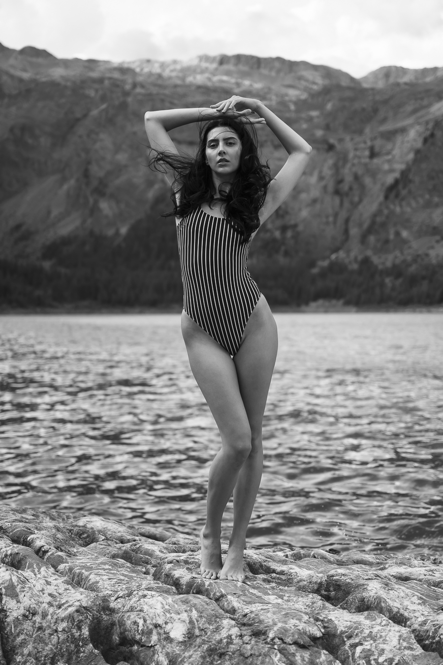 En maillot de bain, la modèle pose devant un lac artificiel, au barrage du Rawil. Debout sur les rochers, elle fixe la caméra.